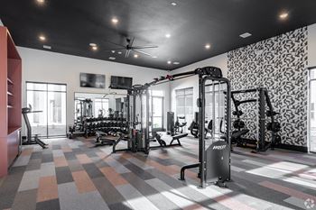 A gym with a variety of equipment including a treadmill, weights, and a television.